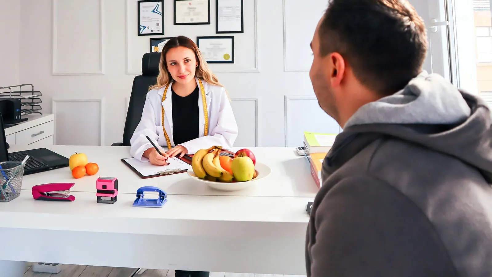 Nutricionista e paciente conversando em consulta acolhedora, escritório com luz natural quente