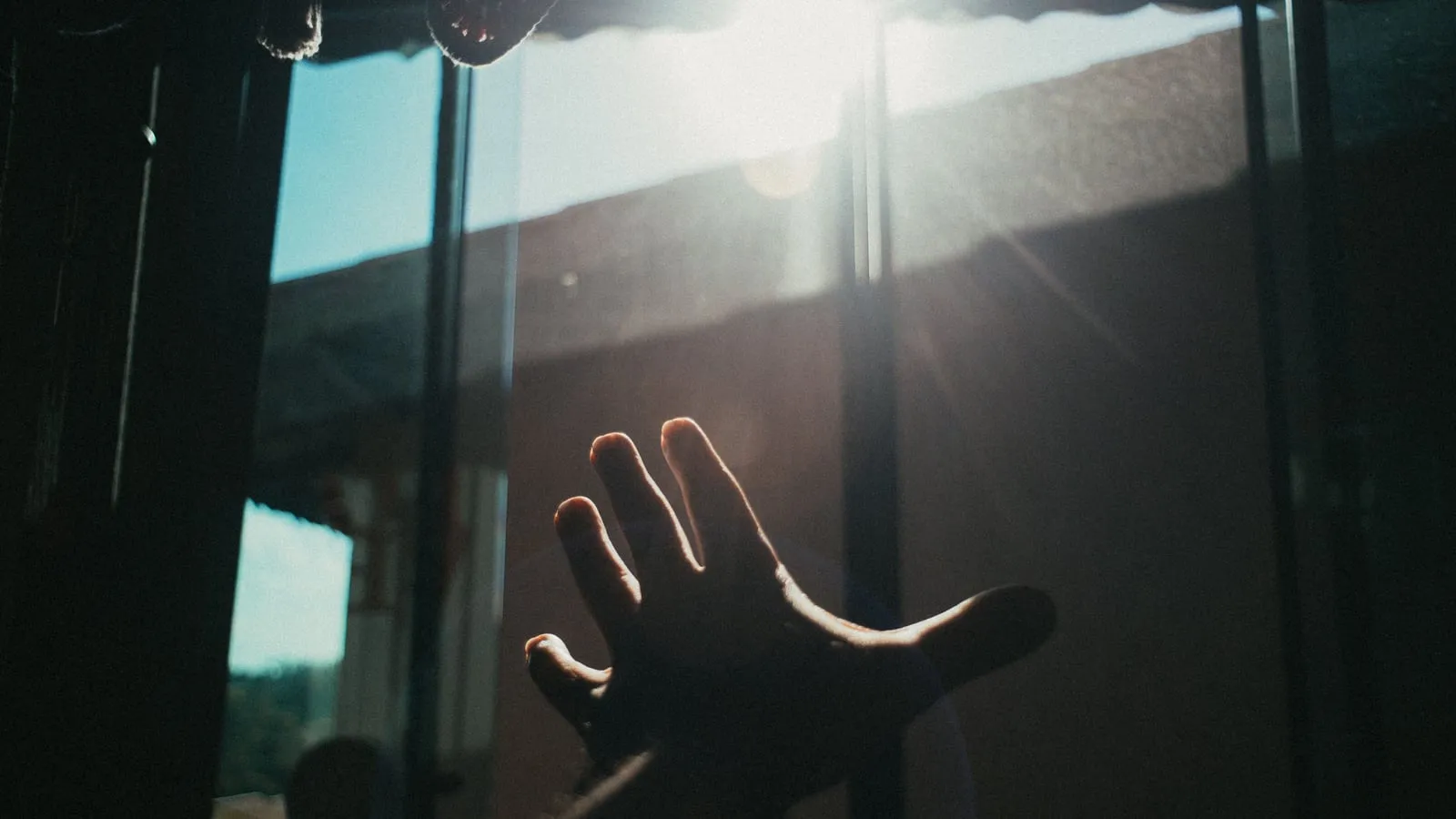 Mão estendida em direção à luz natural que entra por uma janela, simbolizando esperança e o caminho para o tratamento da depressão