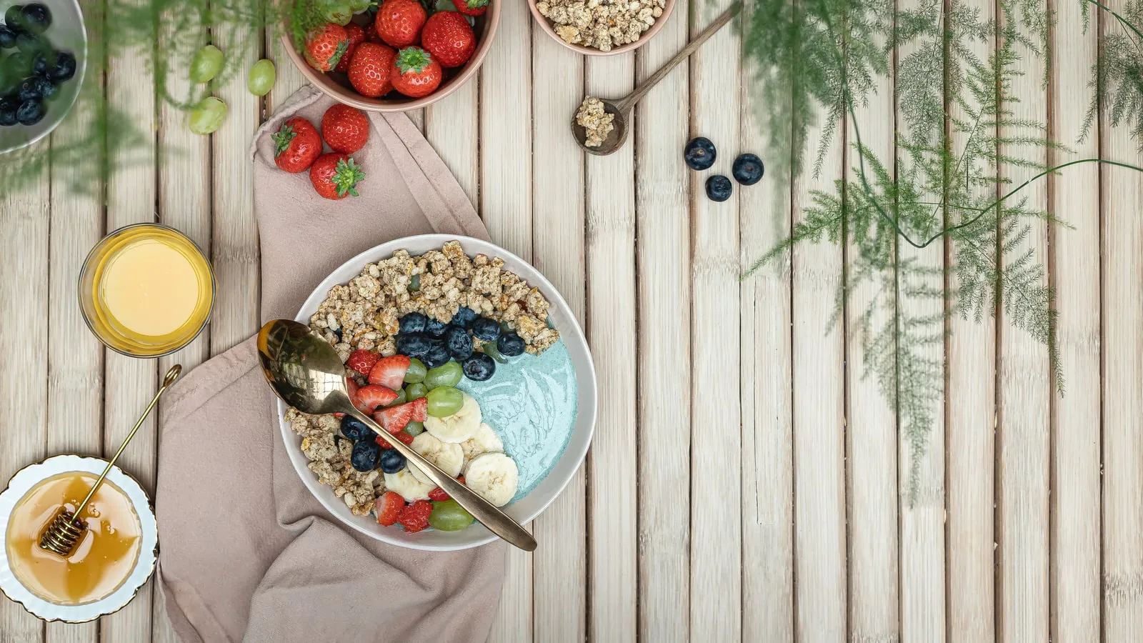 Tigela de café da manhã com frutas frescas coloridas, granola e mel sobre mesa de madeira rústica em luz natural quente